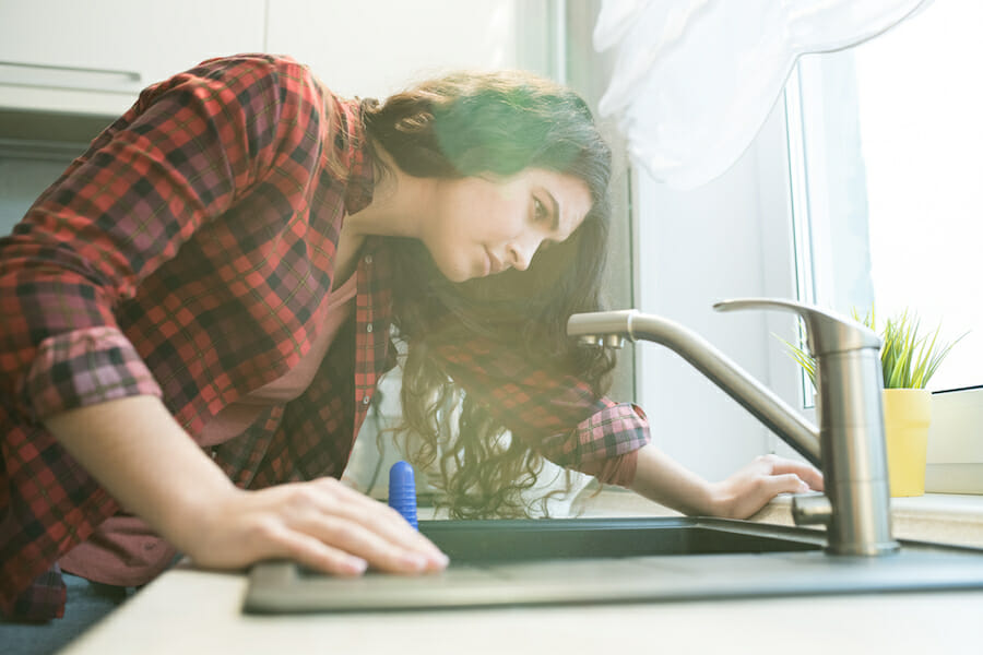 woman checking water from home tap; water softener lifespan