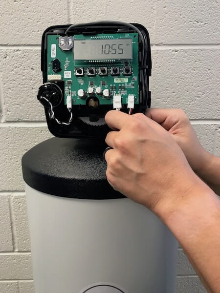 man adjusting water softener settings