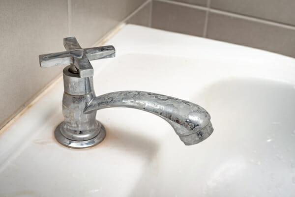 A bathroom sink faucet with visible lime and mineral deposits on the metal surface