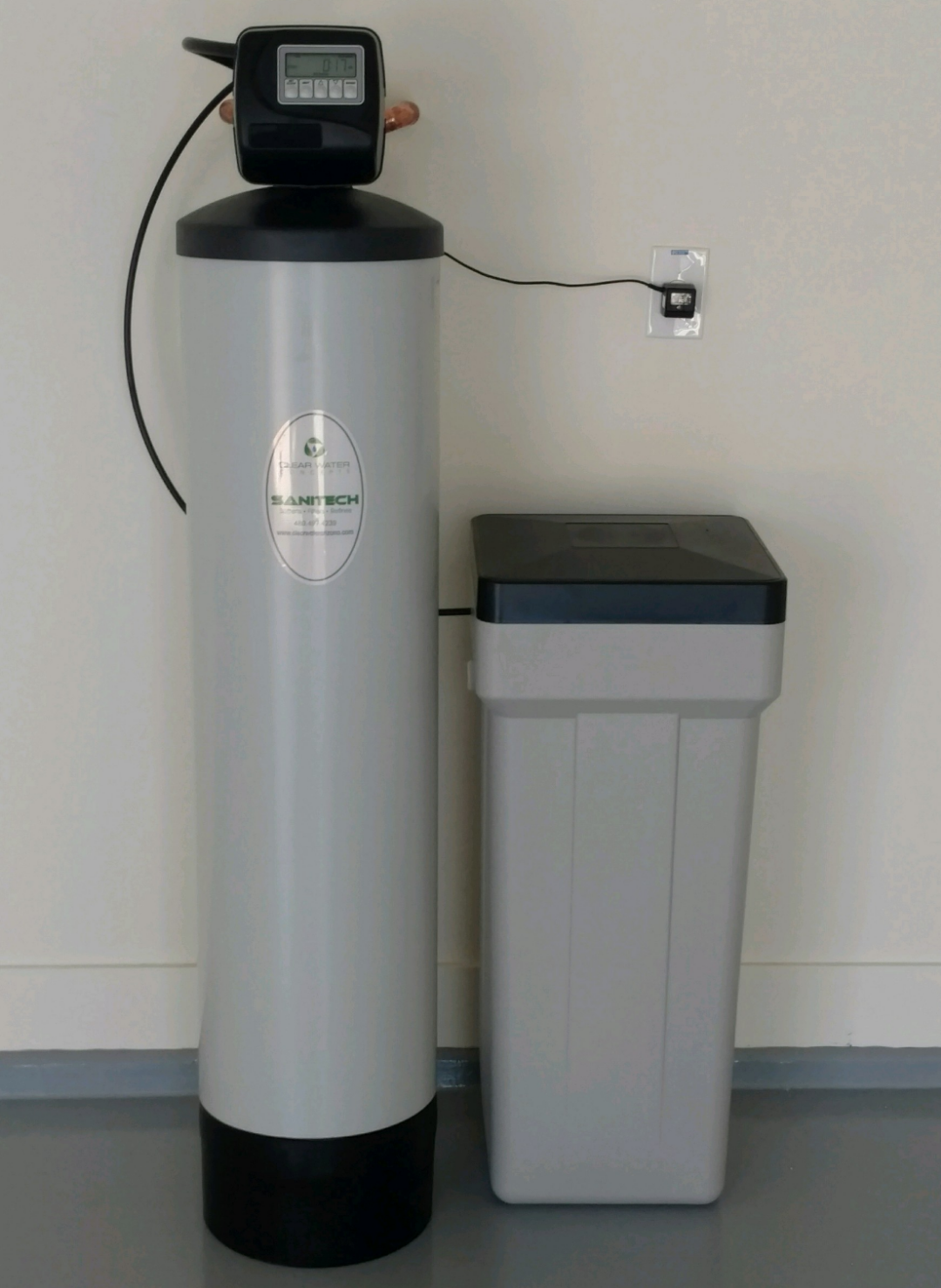 Installed water softener system against a wall, showing main tank and brine tank for water conditioning