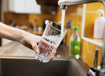 Filtered water from a tap into a glass, highlighting the importance of clean drinking water