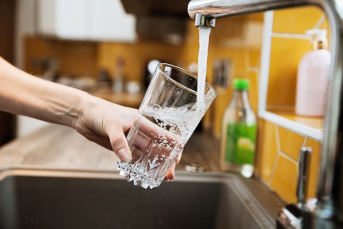 Filtered water from a tap into a glass, highlighting the importance of clean drinking water