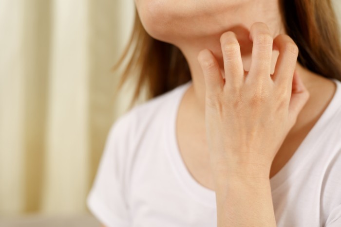 Effects of hard water on skin, including dryness and itching, depicted by a person scratching
