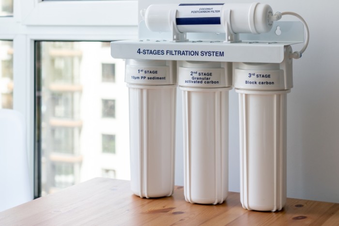 A four-stage water filtration system on a wooden table, demonstrating advanced water purification technology