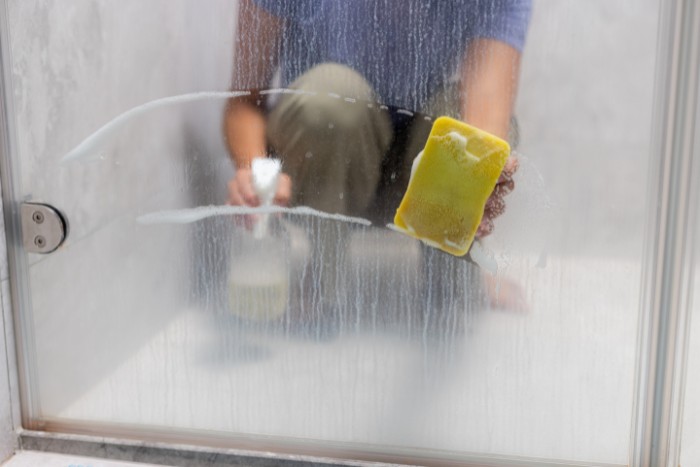 Removing hard water residue from a shower glass door using cleaning tools