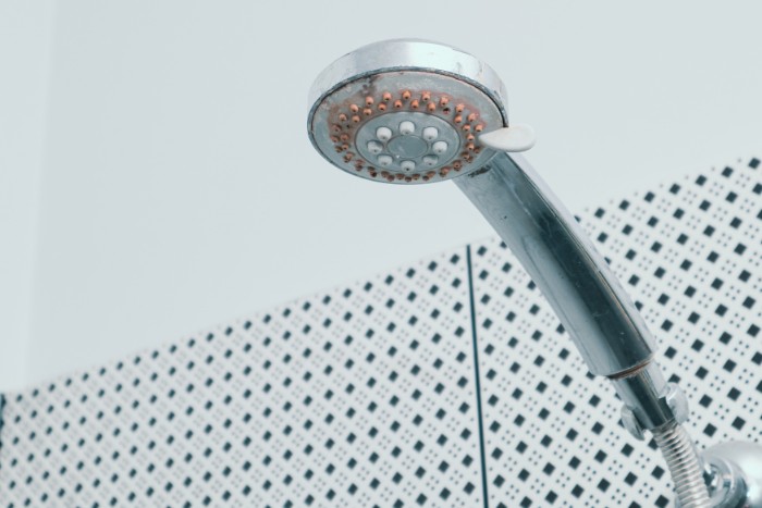 Showerhead with visible mineral deposits caused by hard water buildup
