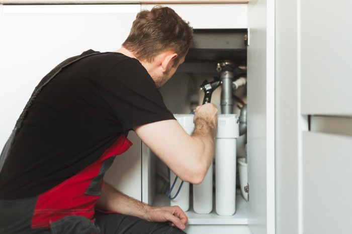 Professional setting up a water softener unit to reduce hard water effects in a home