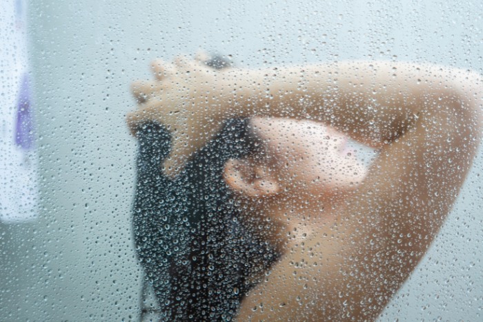 Woman enjoying a shower with soft water, highlighting benefits for hair and skin health
