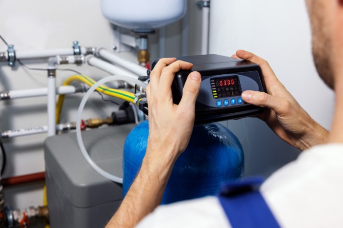 Technician calibrating water softener settings to ensure efficiency