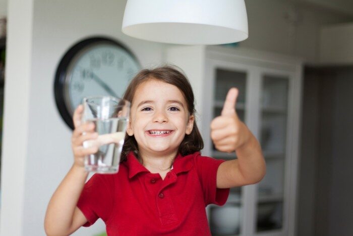 Child enjoying clean drinking water at home after improving water quality with a filtration system