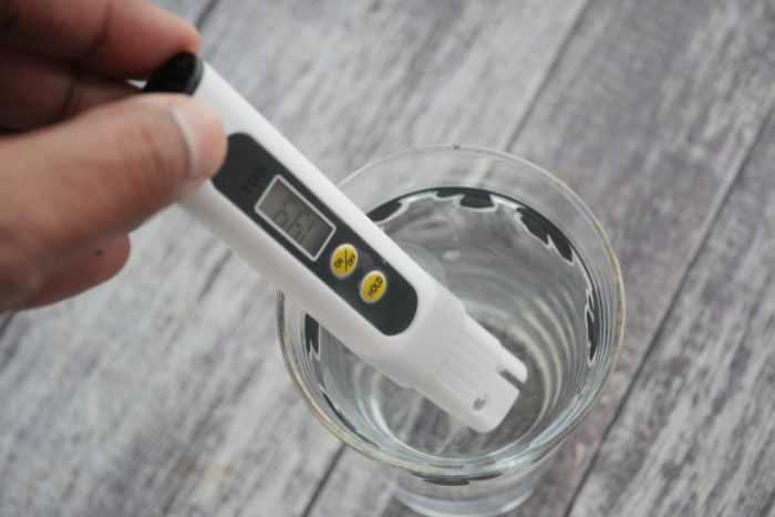 Handheld meter checking water hardness before and after water softener cleaning